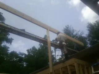 Carpenter setting a ridge beam over a new addition frame — Ice Dam Removal by Roofing Brothers in Lime Ridge