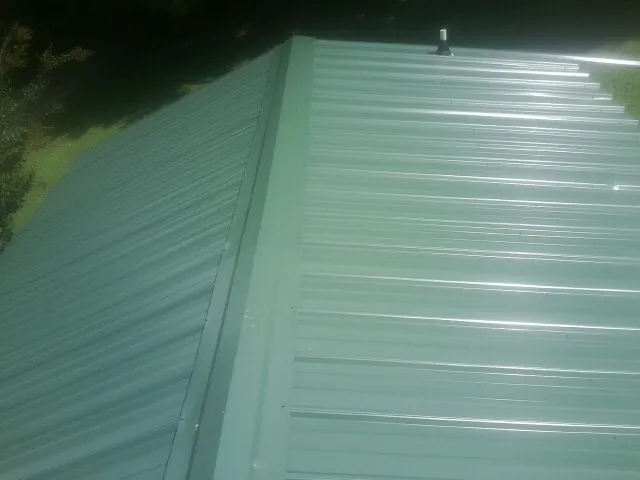 New green metal panels meeting at the ridge of a roof — Flat Roof Repair work by our crew in Lime Ridge