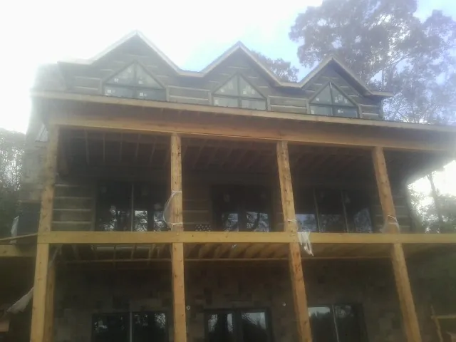 Dormers and porch framing on a large log home under construction — Roof Coating work by our crew in Lime Ridge
