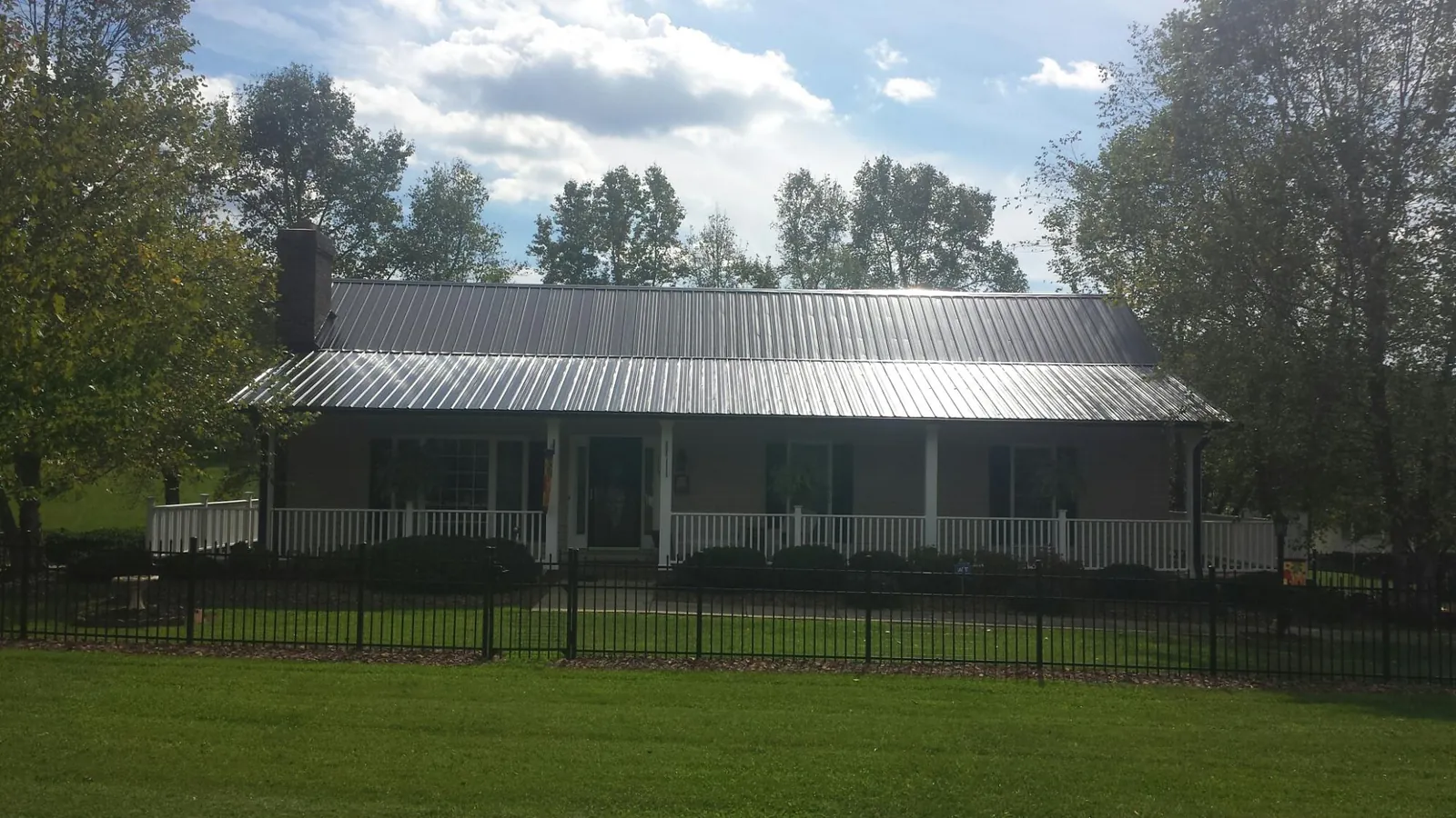 Gray metal roof on a brick ranch with a full width front porch — Gutter Guard Installation work by our crew in Lime Ridge