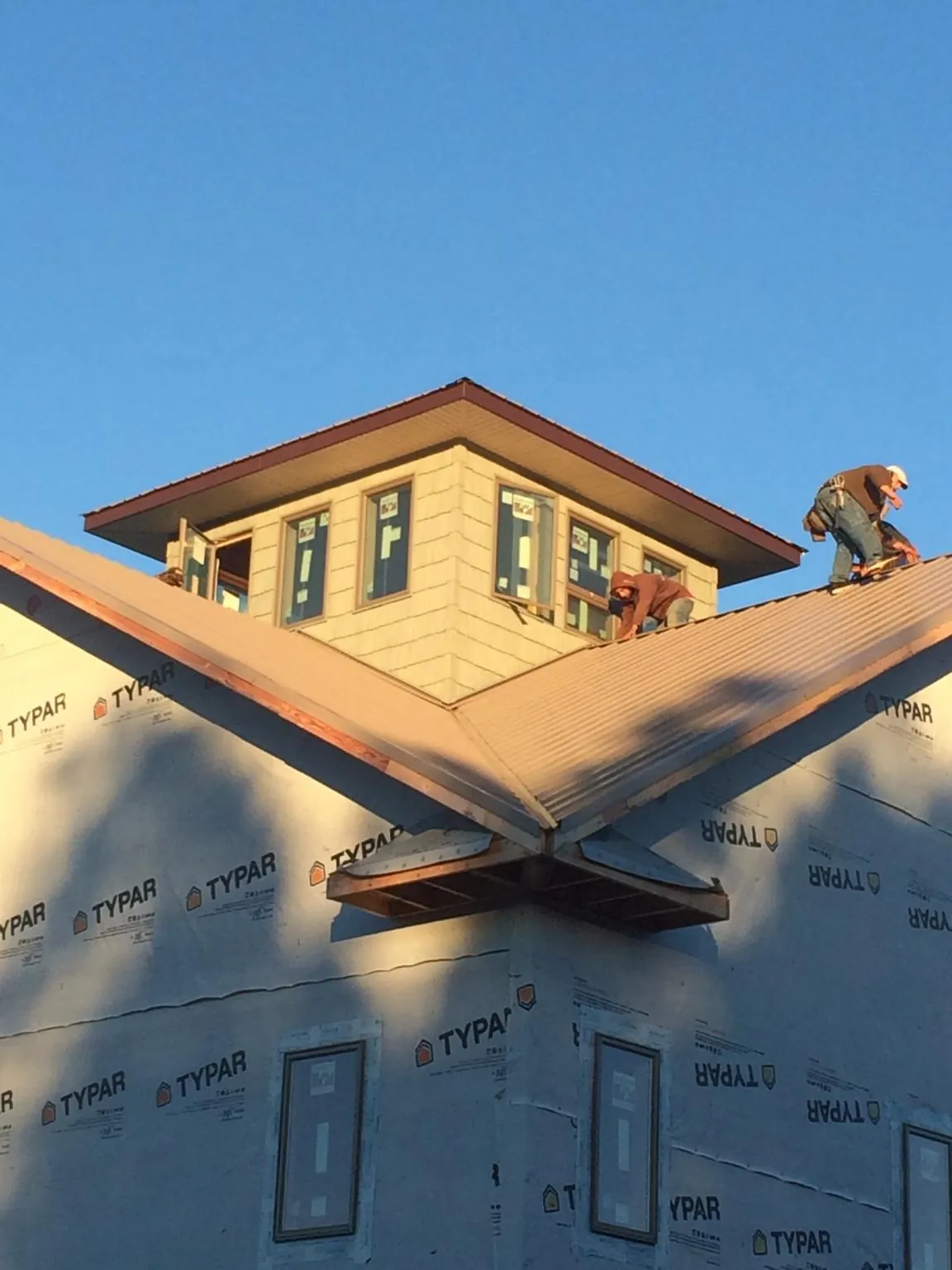 Roofers working around a rooftop cupola on a new metal roof at sunset — Roof Waterproofing in Lime Ridge by Roofing Brothers